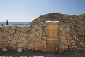 Stone wall with wooden gate and view of a wide landscape under a blue sky