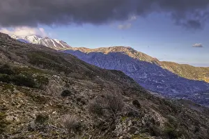 Stony mountain landscape with snow-covered peaks under a slightly cloudy sky