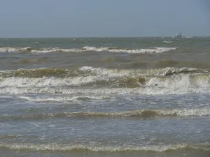 Stormy sea with strong waves and a boat on the horizon