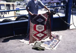 Street vendor offering a Turkish carpet for sale in Cannakale, Turkey (1997)