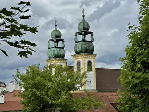 Two striking steeples rise above the trees against a dramatic sky