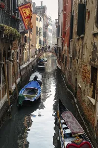 Strollers on a small bridge, boats on a canal