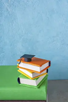 Student paper cap lies on a stack of books on a blue background
