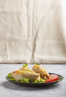 Stuffed baked squid with greens on a blue ceramic plate on a gray concrete background