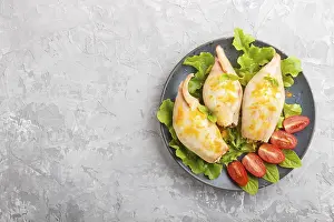 Stuffed baked squid with greens on a blue ceramic plate on a gray concrete background