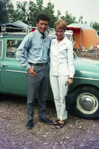 Stylish British couple standing next to their car at a campsite holiday in Spain, 1966