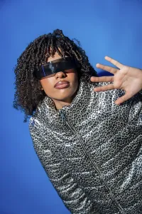 Stylish model showcasing futuristic eyewear and a trendy animal print jacket against a vibrant blue backdrop