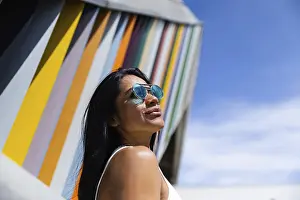 A stylish woman wearing a colorful outfit poses confidently against a backdrop of modern architecture