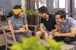 Three stylish and young adult friends celebrating holidays on a terrace of a bar