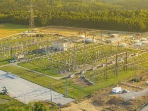 Substation with complex steel structures and technology surrounded by forests and green meadows