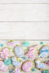 Sugar sprinkles and Easter frosted cookies in shape of egg chicken and rabbit on white wooden table background