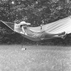 Summer in the 1960s. A lady is lying comfortably in a hammock talking on the phone. Sweden 1961