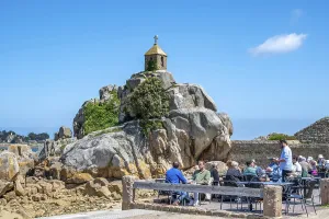 Summer cafe terrace with guests in front of the Oratoire aur Granit Rocks