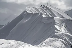 Summit cross of the Hoeferspitze with covered summit ridge and mountaineers