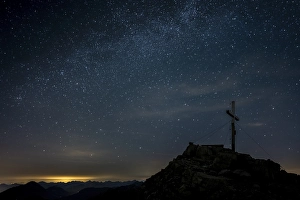 Summit cross of the Namloser Wetterspitze with starry sky with Lechtaler Alps