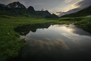 Summit in the morning light with dramatic clouds and stream in the foreground