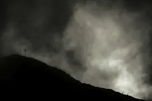 Summit of the Sulzfluh with ascending mountaineers and dramatic cloudy sky