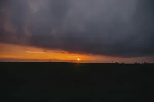 The sun sets behind clouds creating a dramatic