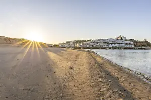 Sunrise on the Atlantic, skyline of a fishing village behind a harbour