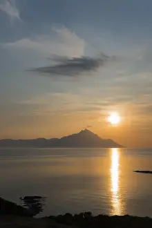 Sunrise over a mountain with clouds and reflections on the water surface