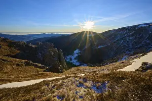 Sunrise over a snow-covered valley surrounded by mountains and rocks