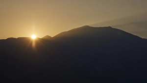 Sunrise, sun solidifies behind the double peak of Psiloritis