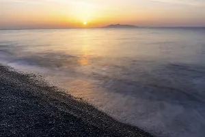 Sunrise, view from the lava beach Kamari to the island Anafi