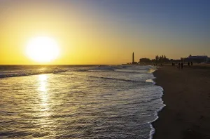 Sunset at the beach of Maspalomas with lighthouse Faro de Maspalomas