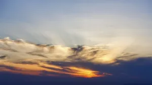Sunset behind cloud cover, sunbeams