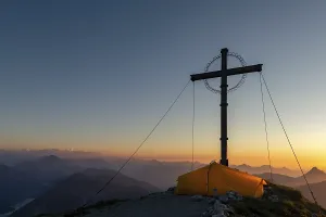 Sunset over Lechtal mountains, in the foreground summit cross of the Geierkopf with tent