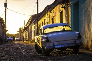 Sunset light in late afternoon shining on beautiful street with a white oldtimer in Trinidad