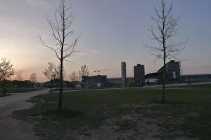 Sunset over a park in Berlin with scattered trees and modern city architecture in the background