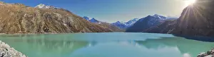 Sunshine over a turquoise lake in the mountains with snow-capped peaks