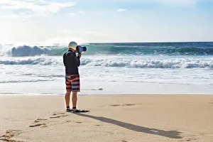 A surf photographer taking photographs by the shore at Banzai Pipeline