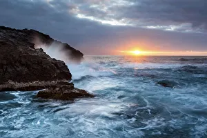 Surf, rocky coast with foaming waves at sunset