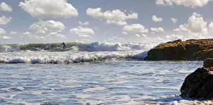 Surfer in the surf on the Pacific beach near Cambria