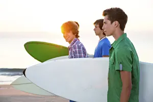 Surfer teen boys group walking at beach shore on sunshine or sunset
