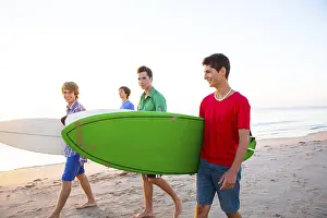 Surfer teen boys group walking at beach shore on sunshine or sunset