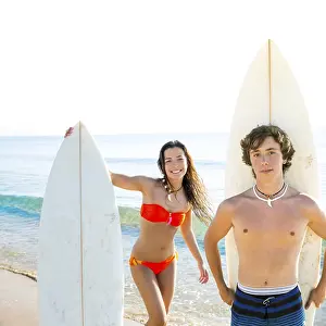 Surfers boy and teen girl with surfboard in beach shore