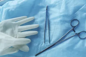 Surgical tools and gloves on blue cloth
