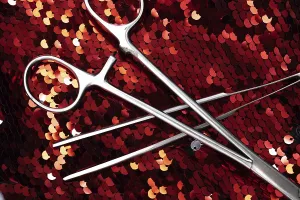 Surgical tools on a red sequin background