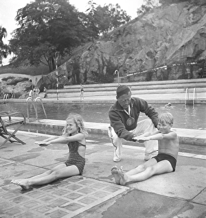 Swimming school in the 1940s. A boy and a girl practice stretching their arms together as you should do when swimming. A swimming instructor is there to give instructions. The place is the swimming school at Vanadisbadet in Stockholm June 1940
