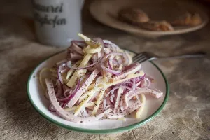 Swiss sausage salad, served in a plate on a wooden table