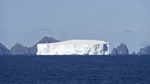 Table iceberg drifts off rocky coastal formations in the South Atlantic