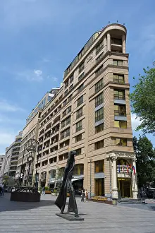 Tall building in an urban environment with a unique statue in front of it