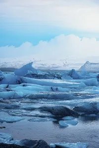 Tall icebergs in cool tones rise over icy water