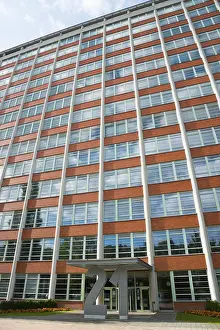 Tall office building with symmetrical window elements and a modern facade under a slightly cloudy sky