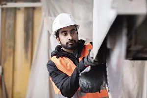 Framed Print : Technician with beard and helmet works in a workshop