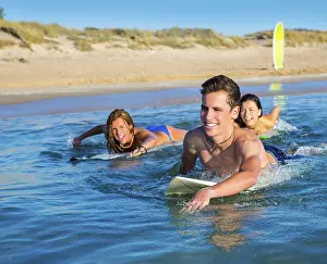 Teenager surfer group boys and girls swimming over the surfboard