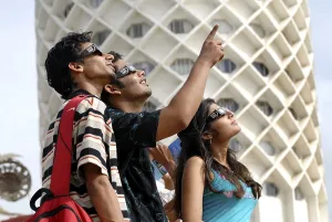 Three teenagers watch partial solar eclipse by wearing a protected filter on 1st August 2008 at Nehru Centre Bombay
